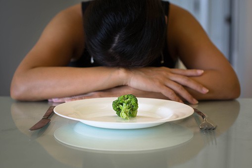 Woman distressed with tiny piece of food in front of her